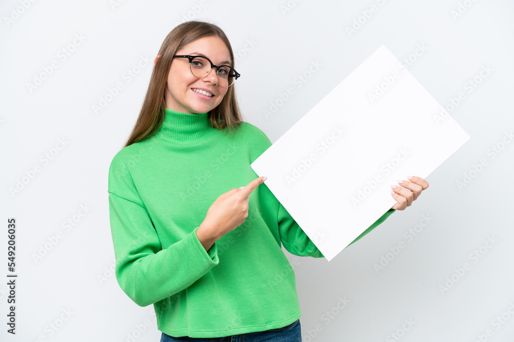 Young caucasian woman isolated on white background holding an empty placard with happy expression and pointing it Young caucasian woman isolated on white background holding an empty placard with happy expression and pointing it