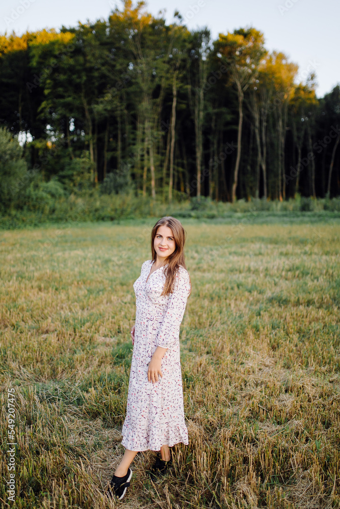 Young woman with beautiful hair posing in field at sunset. Fashion, independence Young woman with beautiful hair posing in field at sunset. Fashion, independence