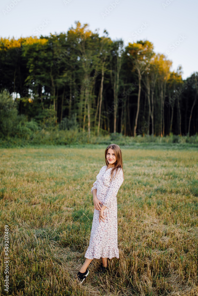 Young woman with beautiful hair posing in field at sunset. Fashion, independence Young woman with beautiful hair posing in field at sunset. Fashion, independence