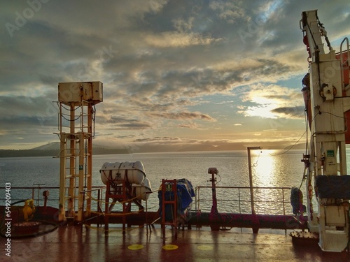 Aerial of metallic construction equipment on a ship by the sea during sunset photo