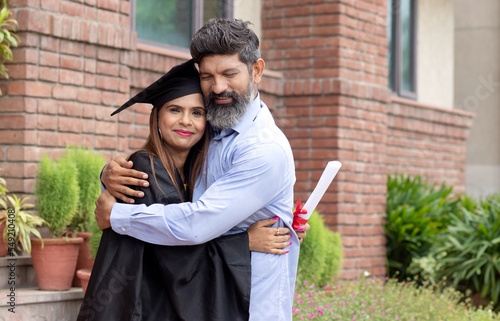 Happy proud Indian father hug daughter at convocation ceremony in university or college, Graduating student. Education.  photo