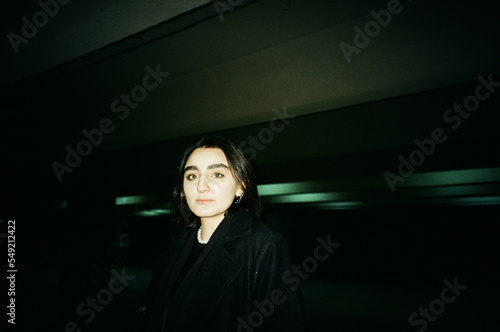 A portrait of a beautiful Caucasian female with dark short hair in a dark underground parking
