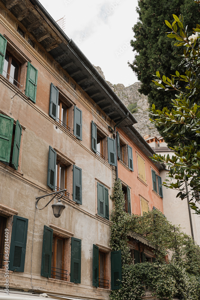 Fototapeta premium Old historic Italian architecture. Traditional European village rustic buildings. Flowers, wooden windows, shutters and pastel walls. Aesthetic summer vacation travel background