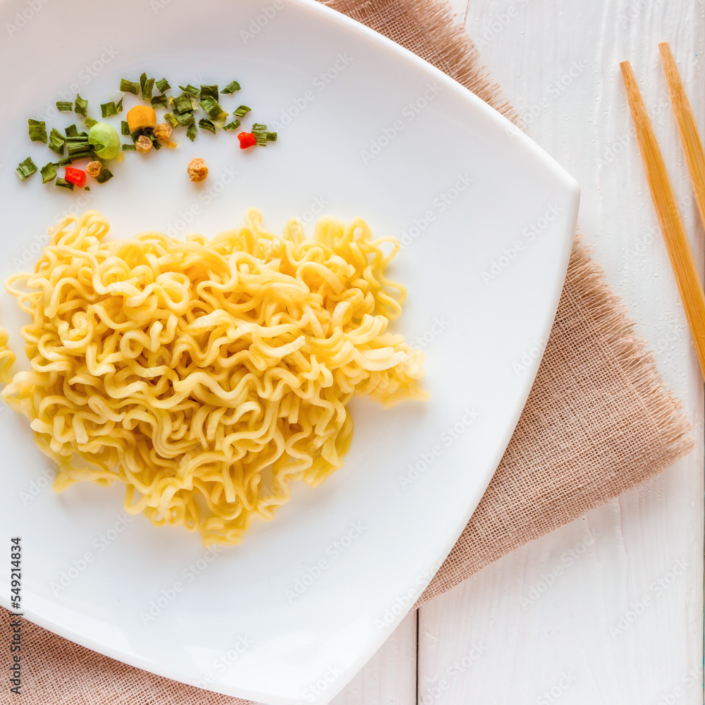 instant noodles and spices on the plate and chopsticks on a white background instant noodles and spices on the plate and chopsticks on a white background