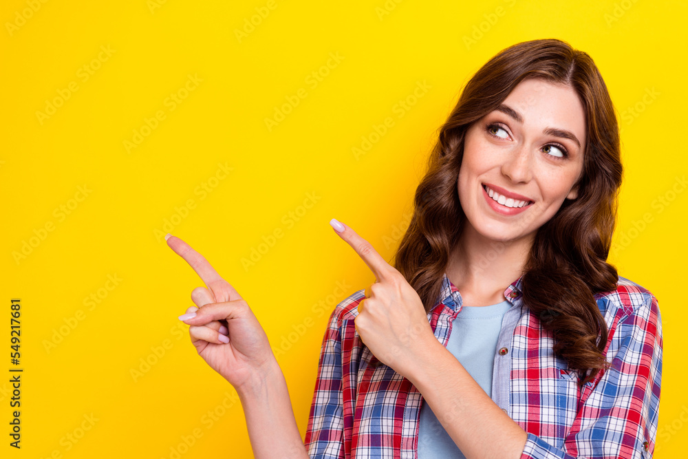 Photo of sweet dreamy lady wear plaid shirt looking pointing two fingers empty space isolated yellow color background Photo of sweet dreamy lady wear plaid shirt looking pointing two fingers empty space isolated yellow color background