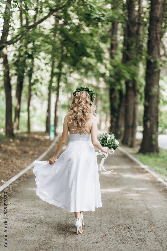A happy young couple in love walk in a garden. A man in a white shirt and a girl in a white light dress are walking in a park A happy young couple in love walk in a garden. A man in a white shirt and a girl in a white light dress are walking in a park