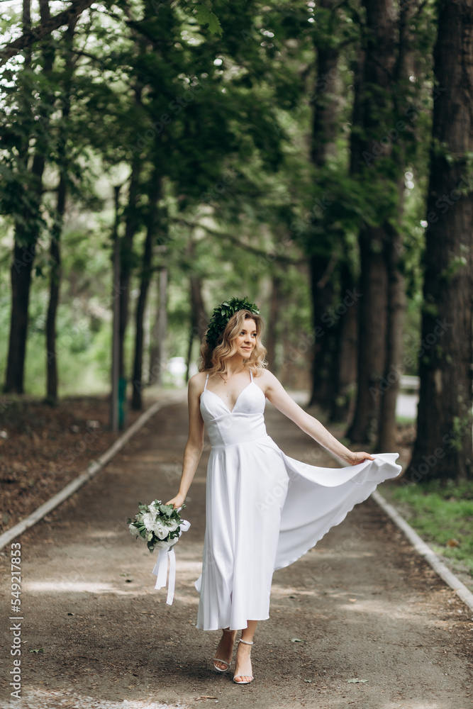 A happy young couple in love walk in a garden. A man in a white shirt and a girl in a white light dress are walking in a park A happy young couple in love walk in a garden. A man in a white shirt and a girl in a white light dress are walking in a park