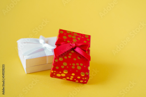 Fototapeta Naklejka Na Ścianę i Meble -  Two red and white gift box with bows isolated on yellow background. Festive wrapping and preparation to winter holidays
