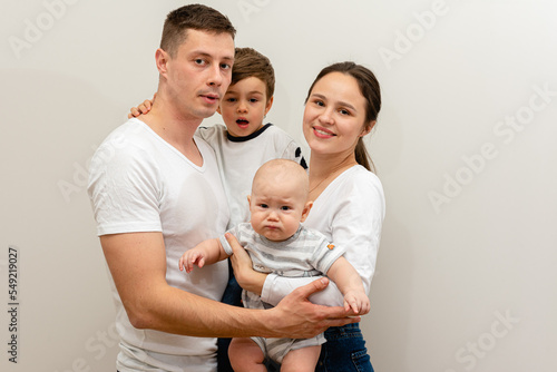 portrait of a young family, father, mother and two small sons, cheerful, friendly and strong family. They smile and hug children in their arms. The concept of a young friendly family 