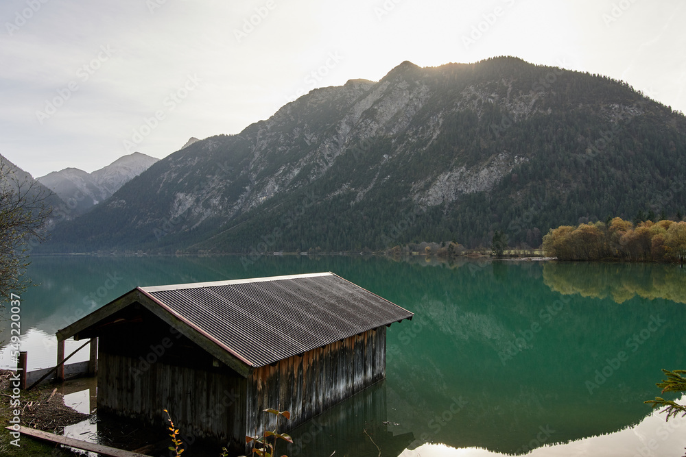 Wooden boathouse with mountains and trees reflecting in lake Heiterwang, Tirol, Austria, Europe.