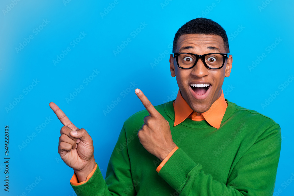 Photo impressed ecstatic crazy man wear orange shirt under green sweatshirt indicating empty space isolated on blue color background Photo impressed ecstatic crazy man wear orange shirt under green sweatshirt indicating empty space isolated on blue color background