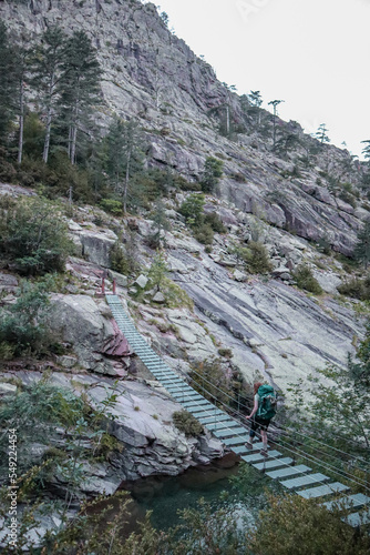 Woman crossing a hanging bridge during the GR20 in Corsica. photo