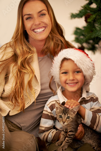 Portrait of family on Christmas, child with cat and mother on festive holiday together in Dallas home. Happy mom giving kitten as gift to kid, celebration of love with pet or relax by christmas tree