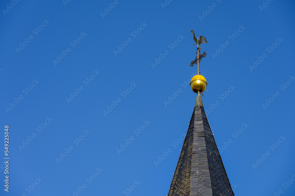 Kirchturmspitze mit Wetterhahn, Kreuz und Turmkugel vor blauem Himmel Kirchturmspitze mit Wetterhahn, Kreuz und Turmkugel vor blauem Himmel