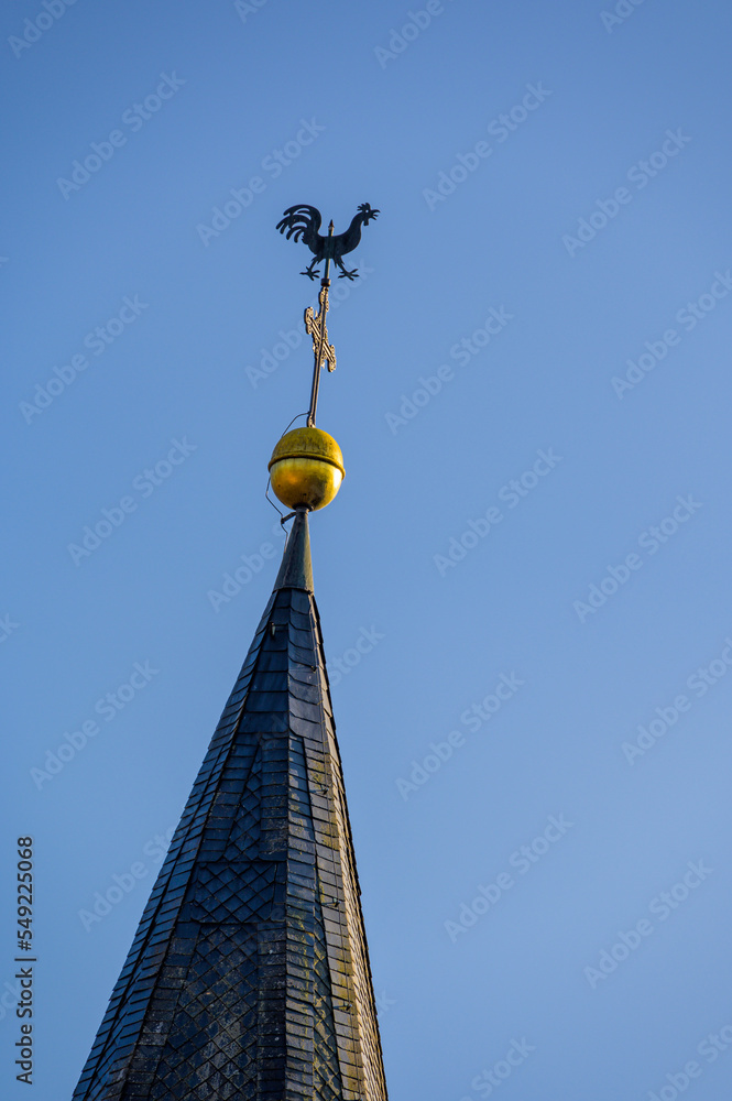 Kirchturmspitze mit Wetterhahn, Kreuz und Turmkugel vor blauem Himmel