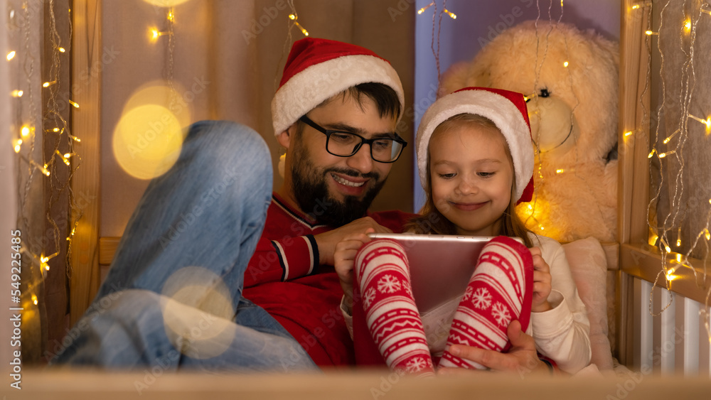 Father and daughter use tablet. Family spend New Years Christmas holiday time