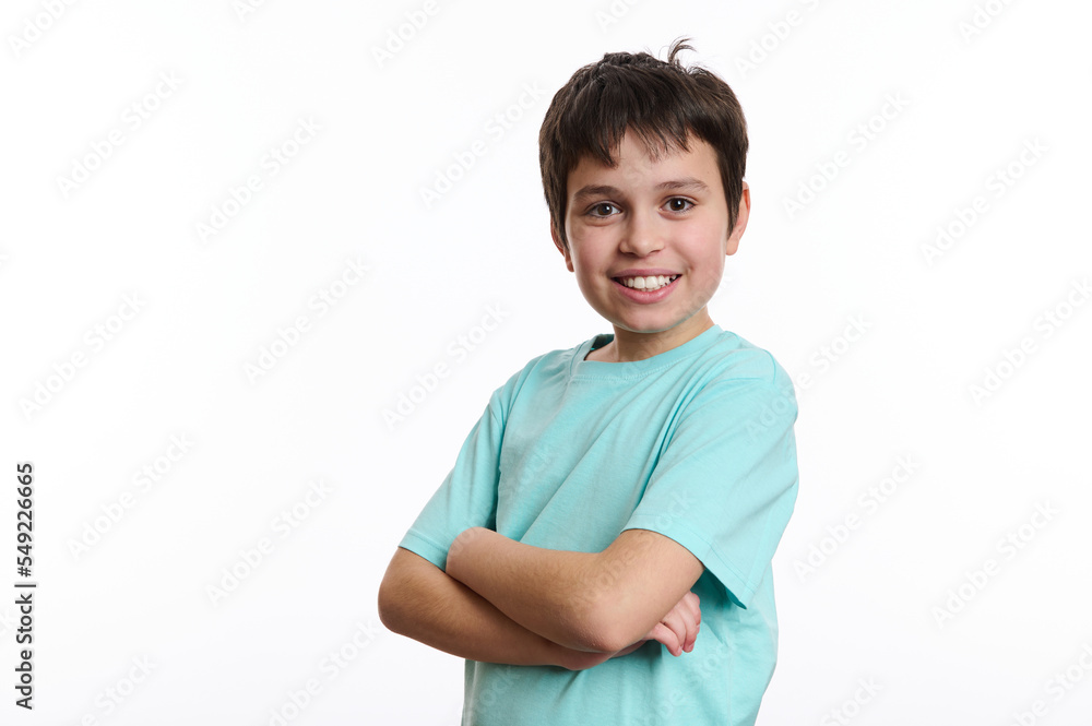Handsome cheerful pre-adolescent boy smiling with beautiful toothy smile, confidently looking at camera, posing with crossed arms over white background with advertising space for you promotional text Handsome cheerful pre-adolescent boy smiling with beautiful toothy smile, confidently looking at camera, posing with crossed arms over white background with advertising space for you promotional text