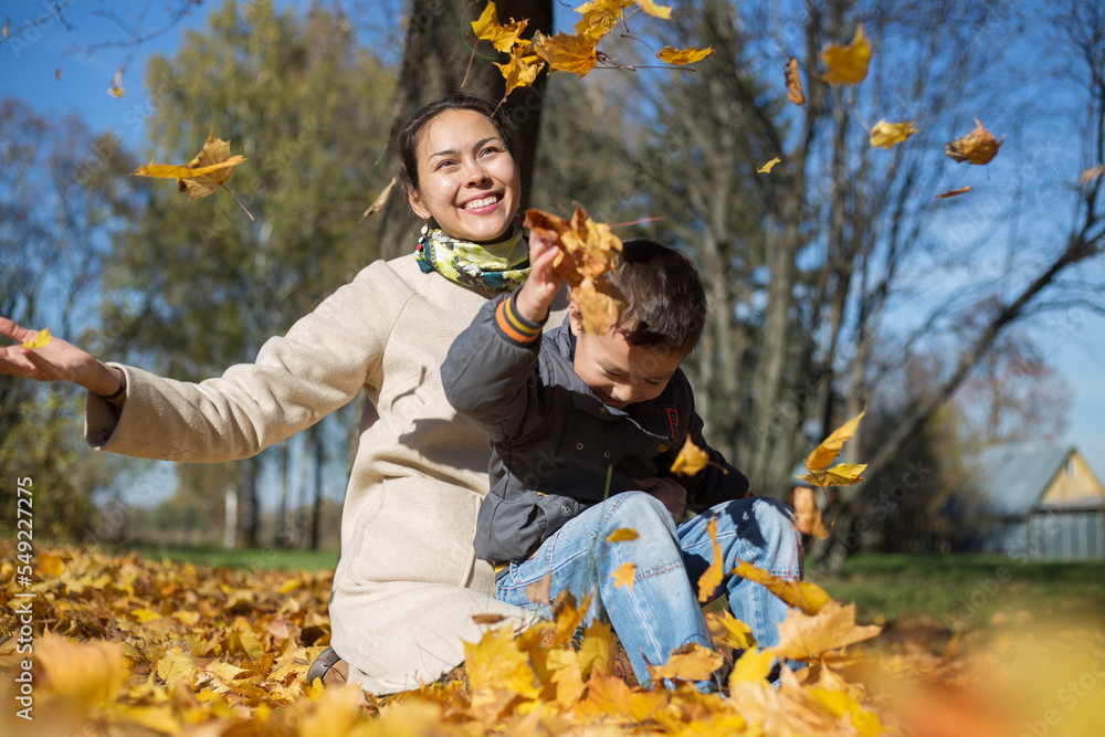 Asian mother and Asian kid boy are playing in a park in autumn Asian mother and Asian kid boy are playing in a park in autumn