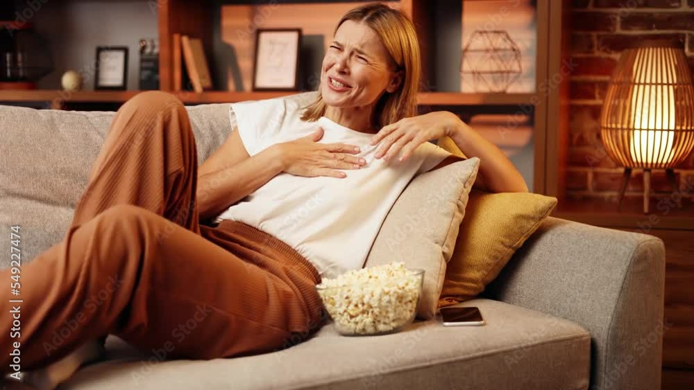 Portrait of happy positive middle aged woman with popcorn laughing while watching comedy movie show serial at home alone. Fun weekend time. . High quality 4k footage Portrait of happy positive middle aged woman with popcorn laughing while watching comedy movie show serial at home alone. Fun weekend time. . High quality 4k footage