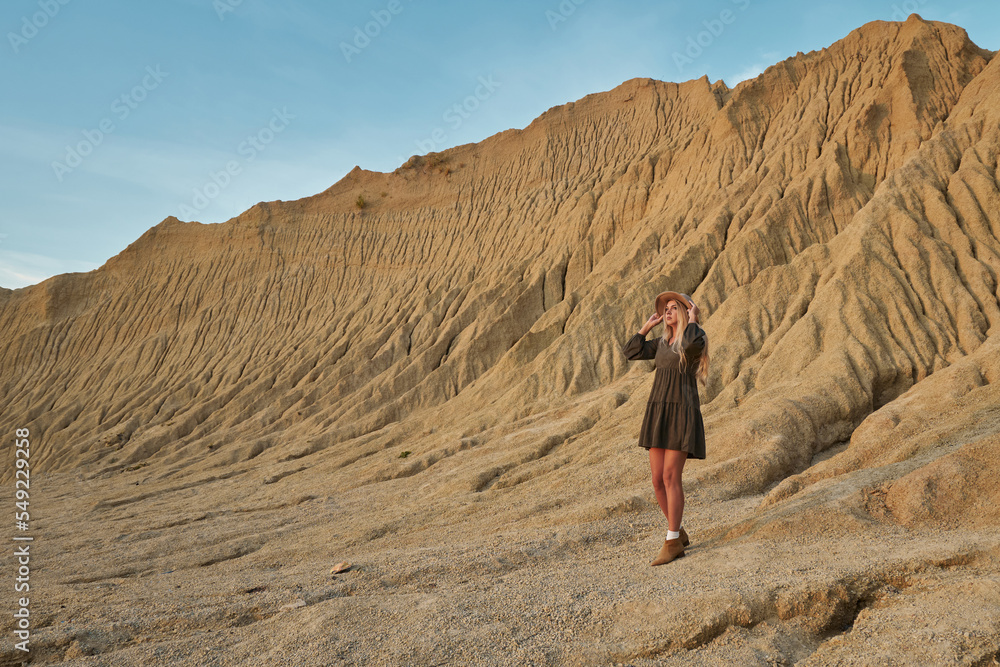 beautiful high sandy mountains and beautiful landscape. young beautiful woman in a hat and dress on a background of beautiful nature