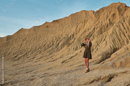 beautiful high sandy mountains and beautiful landscape. young beautiful woman in a hat and dress on a background of beautiful nature