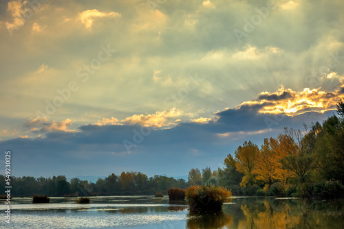 Sunrise over lake, sun hidden behind a cloud. Autumn landscape. Dubnica, Slovakia.