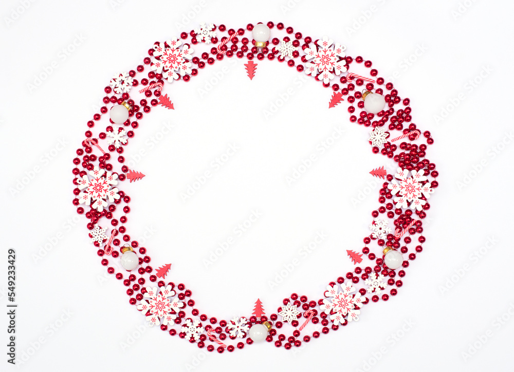 Christmas or winter white background with circle formed of red beads and Xmas decorations. Greeting card mock-up. New Year holiday concept. Flat lay style with copy space