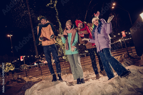Photo picture of four best friend spend winter time together throwing snow up like european christmas atmosphere in city town center outdoors