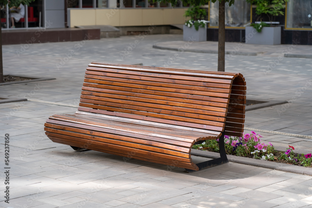 Empty wooden bench with beautiful flowers at city street. Outdoor chair,  urban public furniture, empty plank seat, comfortable bench in recreation  area in town. Stock Photo | Adobe Stock