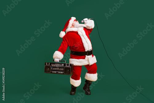 Full size photo of fat crazy grey white hair bearded santa claus sing x-mas christmas song hold boom box wear headwear cap isolated over bright shine color background