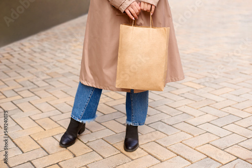 woman holding paper bag with place for text or logo in hands on city street
