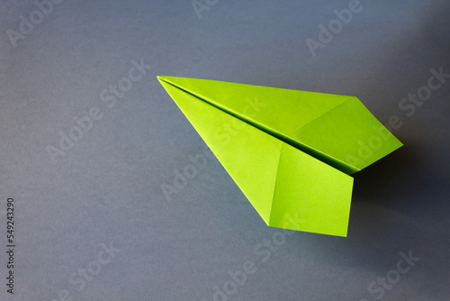 Green paper plane origami isolated on a grey background