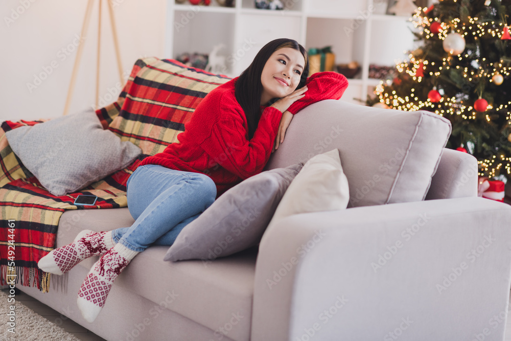 Obraz premium Portrait of thoughtful woman straight hairdo wear red knit pullover laying on couch hands under cheek look empty space in house indoors