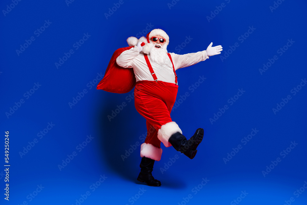 Full length body size view of his he attractive cheerful cheery Santa father carrying big large sack delivery sale discount going isolated bright vivid shine vibrant red color background