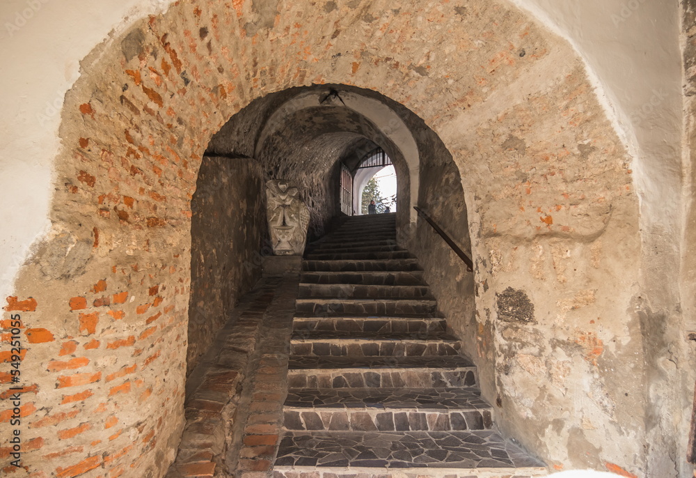 Passage between two parts of the ancient castle with an old stone staircase. Stone arch and steps in the castle. Stone corridor with stairway in ancient castle.