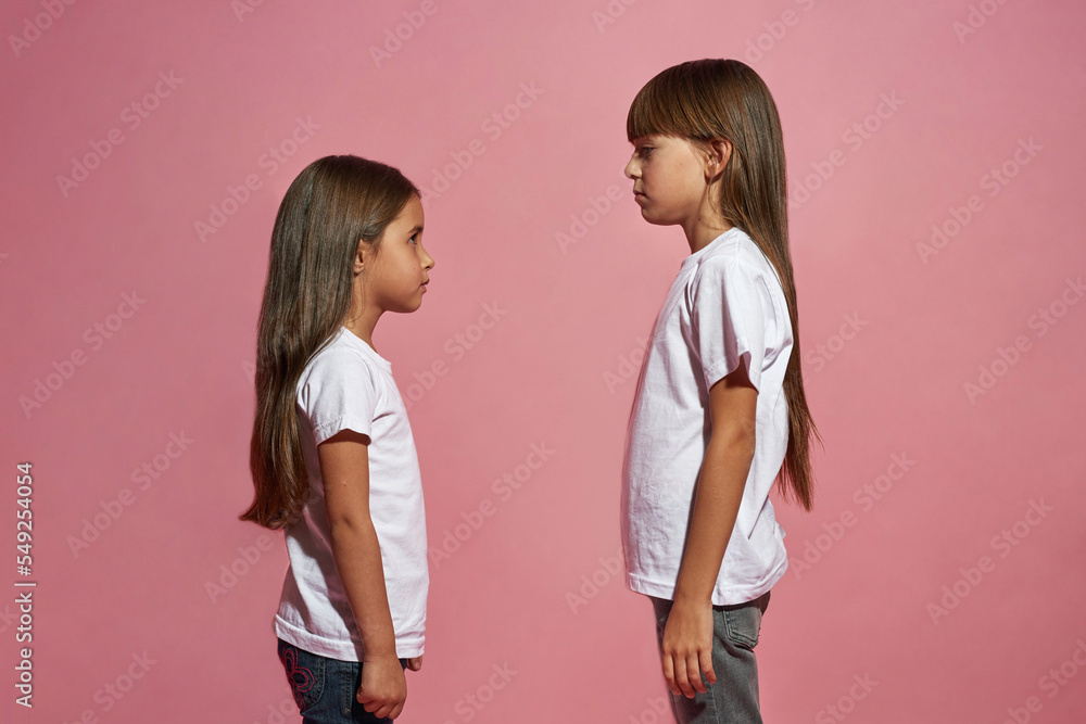 Side of serious little girls looking at each other Side of serious little girls looking at each other