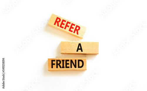 Refer a friend symbol. Concept words Refer a friend on wooden blocks on a beautiful white table white background. Business and refer a friend concept. Copy space.