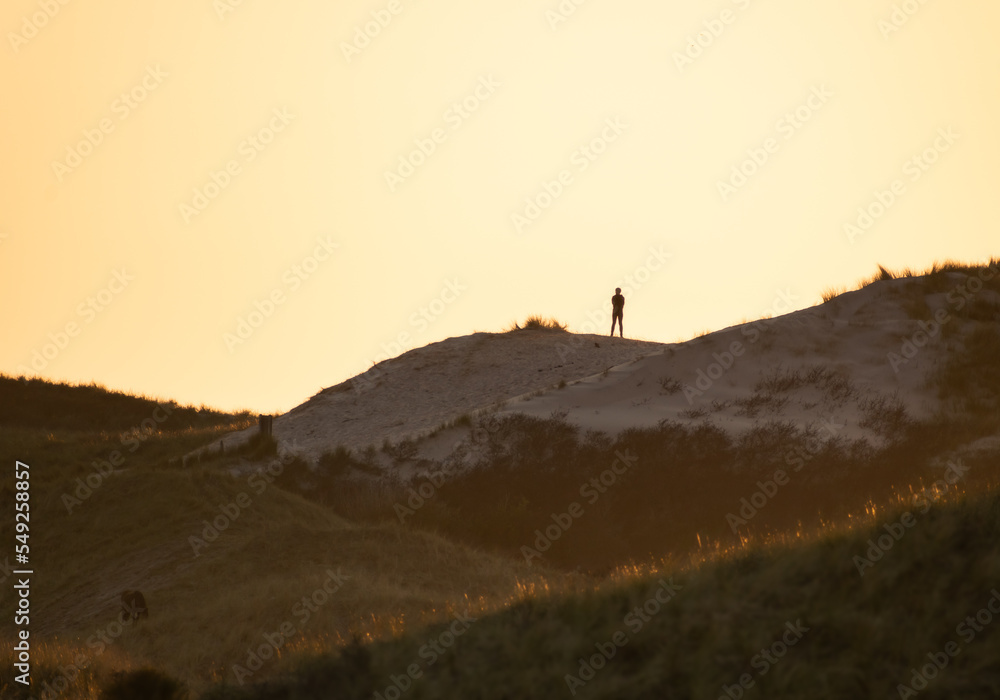 man on top of dune at sunset