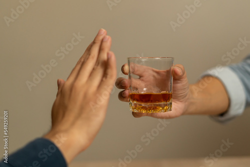 Alcoholism, sad depressed asian young man, male hand holding glass, refuse alcoholic beverage, drink whiskey at night. Treatment of alcohol addiction, having suffered abuse problem alcoholism concept. photo