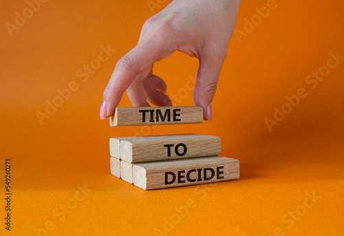 Time to decide symbol. Concept words Time to decide on wooden blocks. Beautiful orange background. Busimessman hand. Business and Time to decide concept. Copy space. photo