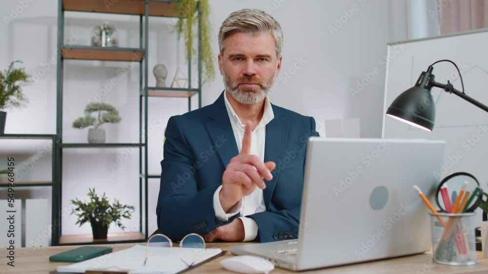 Mature businessman working on laptop computer shakes finger and saying No be careful scolding and giving advice to avoid danger mistake disapproval sign at office. Confident freelancer middle aged man Mature businessman working on laptop computer shakes finger and saying No be careful scolding and giving advice to avoid danger mistake disapproval sign at office. Confident freelancer middle aged man