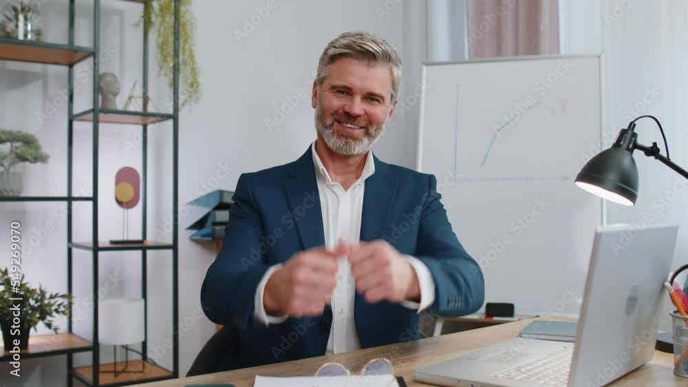 Like. Happy mature businessman working on laptop looking approvingly at camera showing thumbs up, like sign positive something good, positive feedback at office workplace. Freelancer middle aged man Like. Happy mature businessman working on laptop looking approvingly at camera showing thumbs up, like sign positive something good, positive feedback at office workplace. Freelancer middle aged man