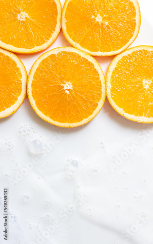 Fresh orange slices in a milk bath. Background for whey fruit drinks. Vertical banner. Selective focus  copy space