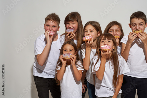 Group of children eating sweet tasty doughnuts