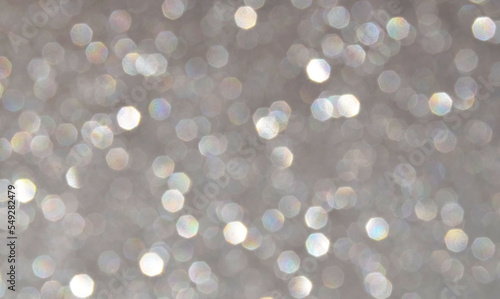 Blurred glitter background in silver colour as a part of Christmas design.Holiday abstract texture with bokeh lights.Fabric sequins.Selective focus. 