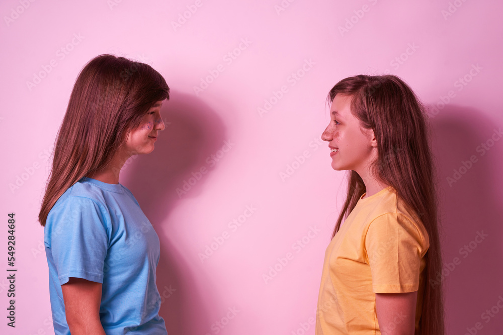 Side view of teenage girls looking at each other Side view of teenage girls looking at each other