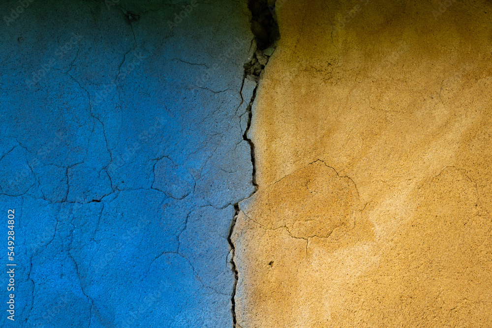 background of toned blue and yellow wall with crack in middle