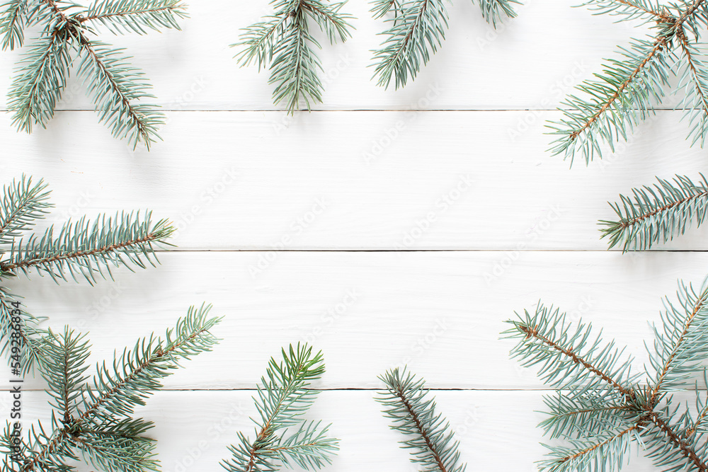 Spruce branches on a white wooden background. Christmas minimalism. Copy space. Flat lay, top view