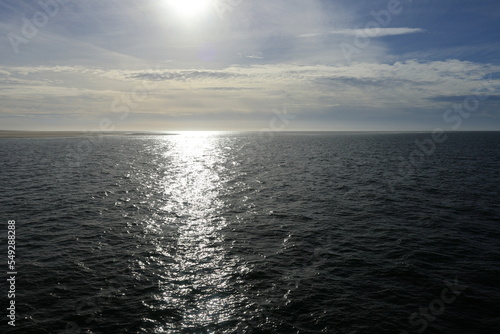 Die Sonne scheint auf das Nordmeer und die Strahlen brechen auf den Wellen