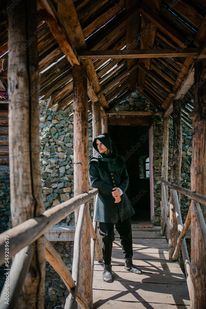 A man in medieval clothes against the background of a stone castle wall. Historical costume. A man in medieval clothes against the background of a stone castle wall. Historical costume.